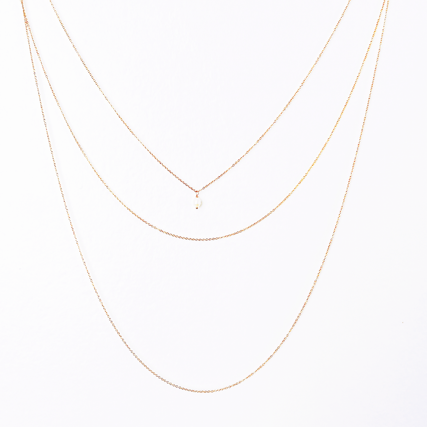 Front and back long necklace featuring three loops with white pearl accents.