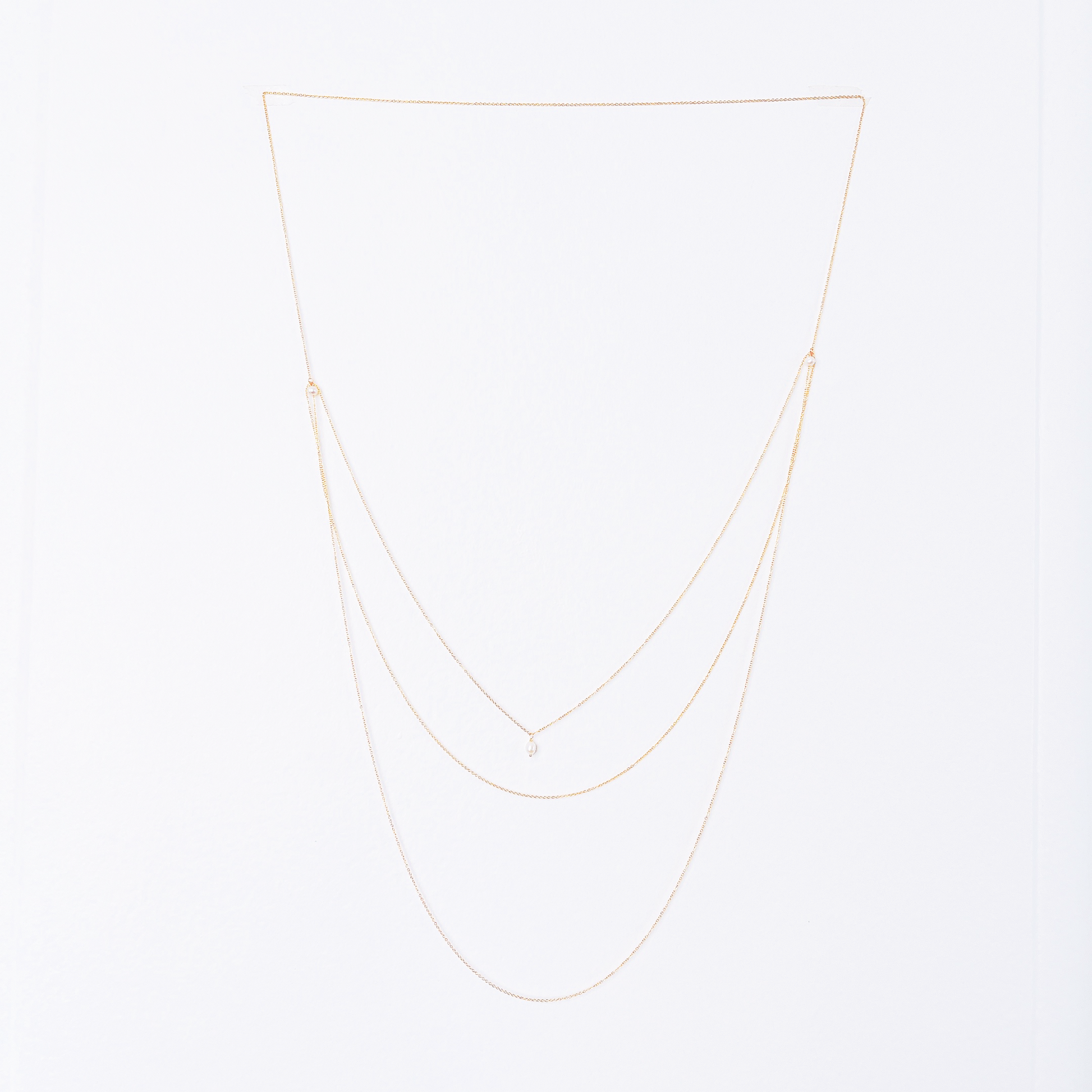 Front and back view of a long necklace with three loops, featuring white pearl beads