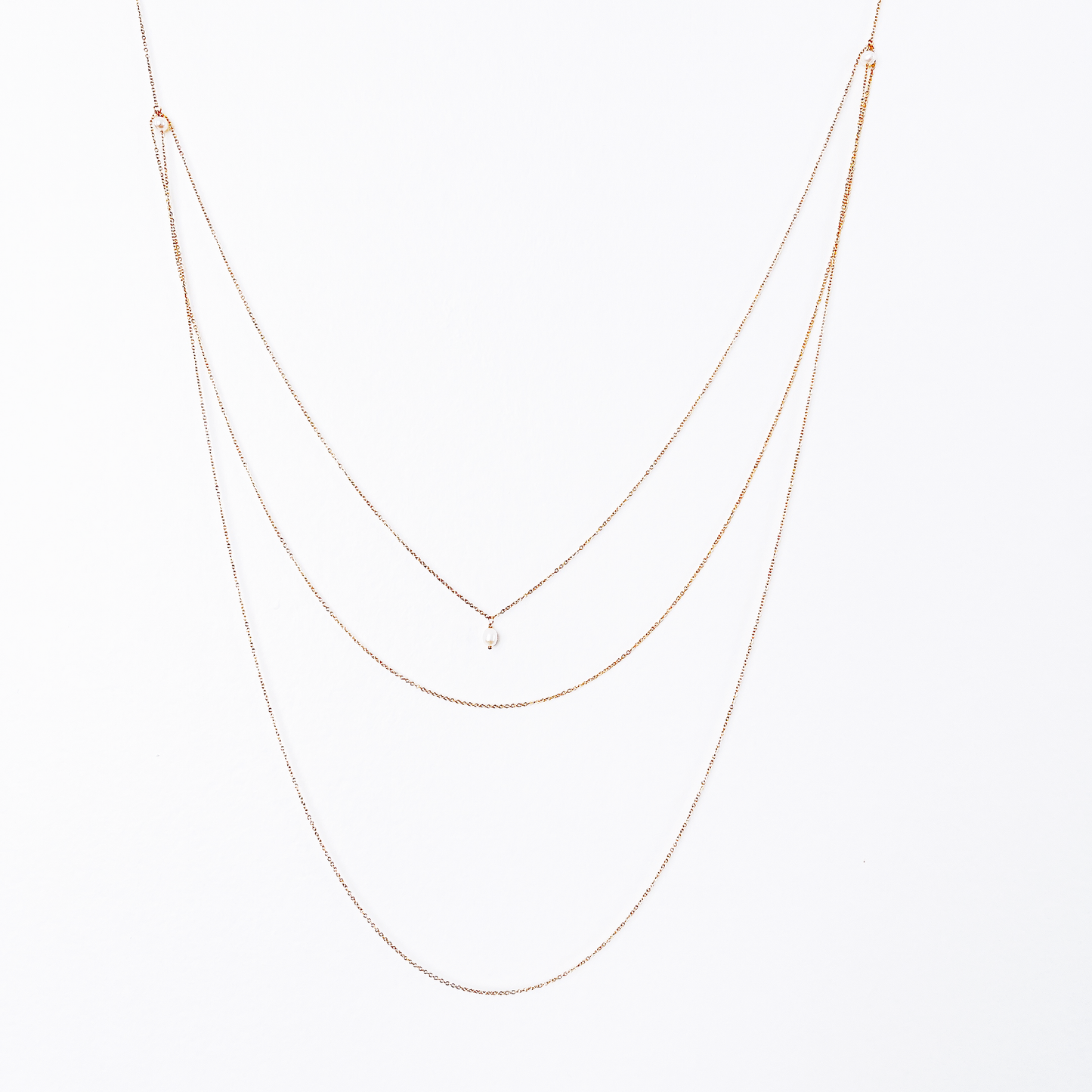 Front and back view of a long necklace with three loops, featuring white pearl beads