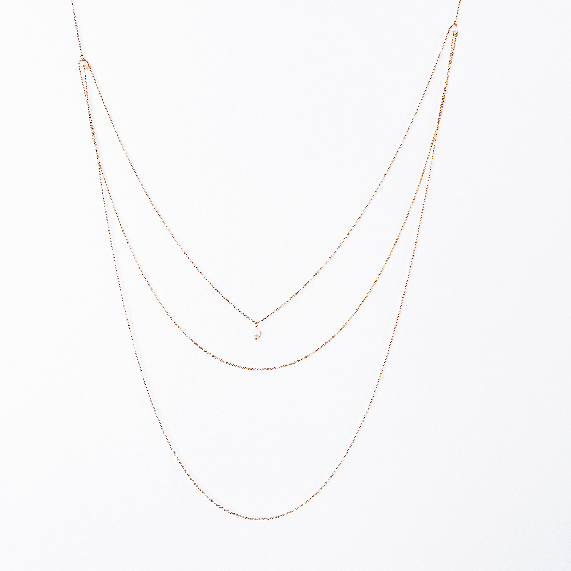 Front and back view of a long necklace with three loops, featuring white pearl beads