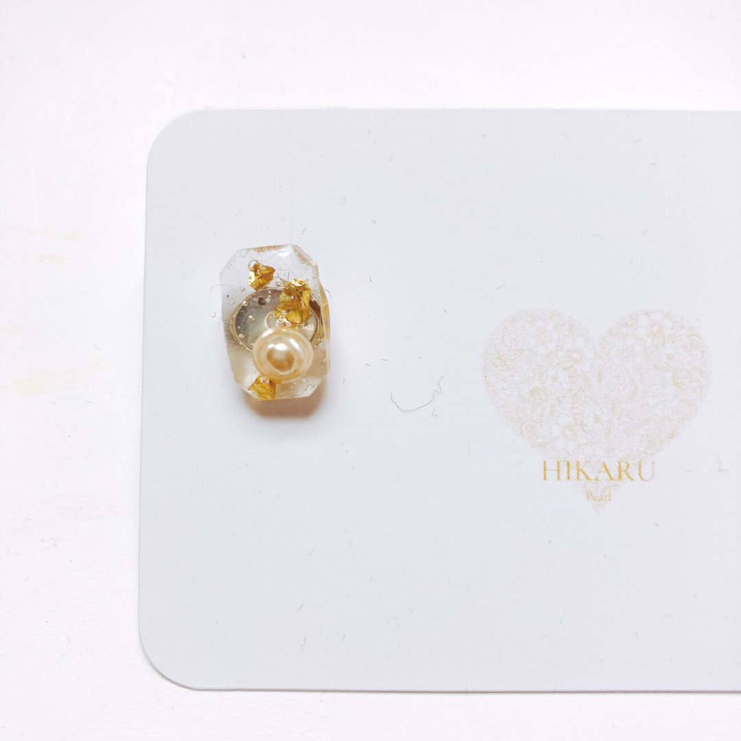 Handmade resin rectangle pendant featuring real gold and golden elements, adorned with a pink freshwater pearl and small gold stones. The pendant measures 10-20mm and showcases a delicate arrangement of floating pearls in transparent resin. A unique, luxurious accessory combining organic and precious materials, adding elegance to any outfit.
